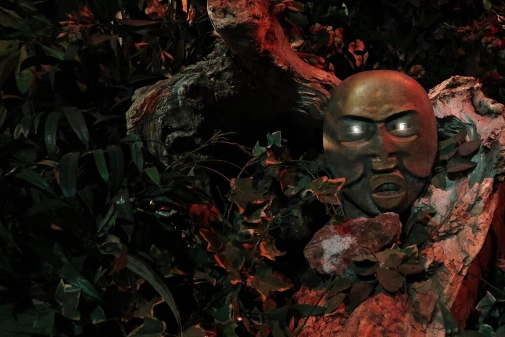Mayan mask hidden between the foliage in the station (© Dark Ride Database)